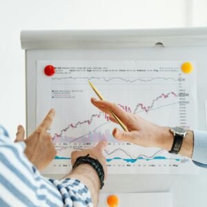 Two people analyzing financial charts on a whiteboard during a business meeting.